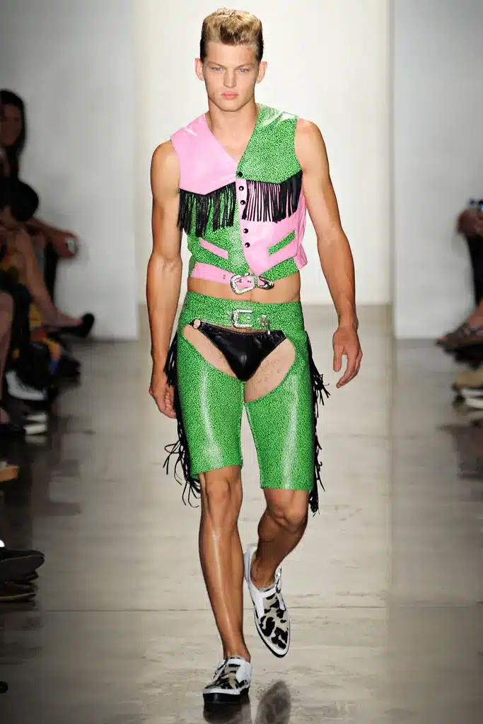 A man in green and pink outfit walking down the runway.