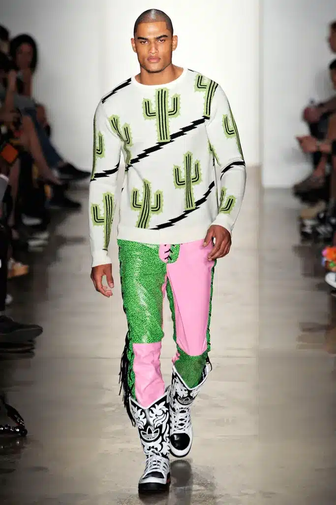 A man in green and pink pants walking down the runway.