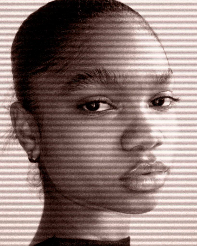 A young woman with a piercing is looking at the camera.