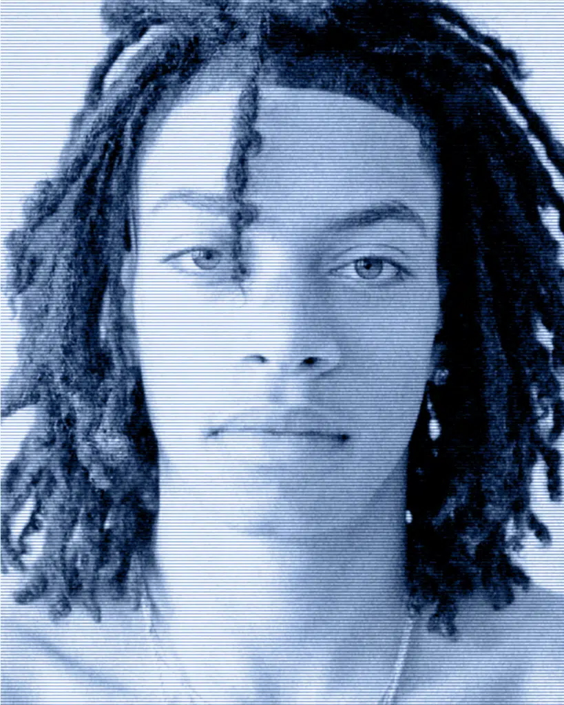 A man with dreadlocks is looking at the camera.