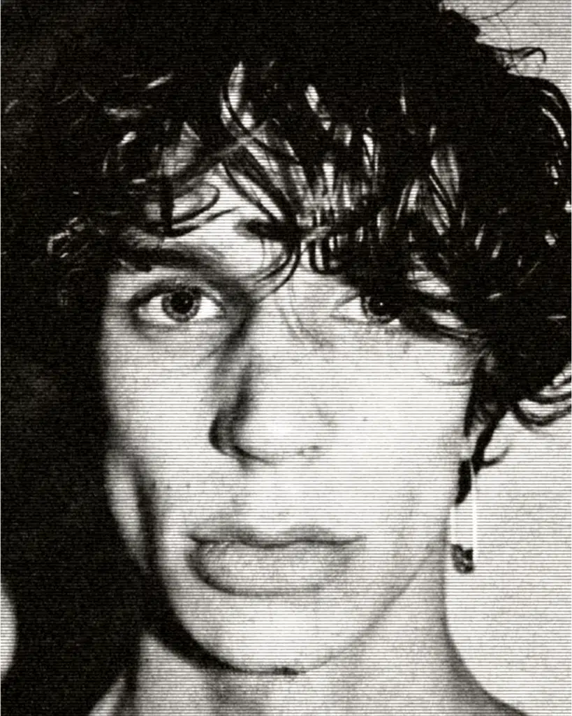 A black and white photo of a man with curly hair.