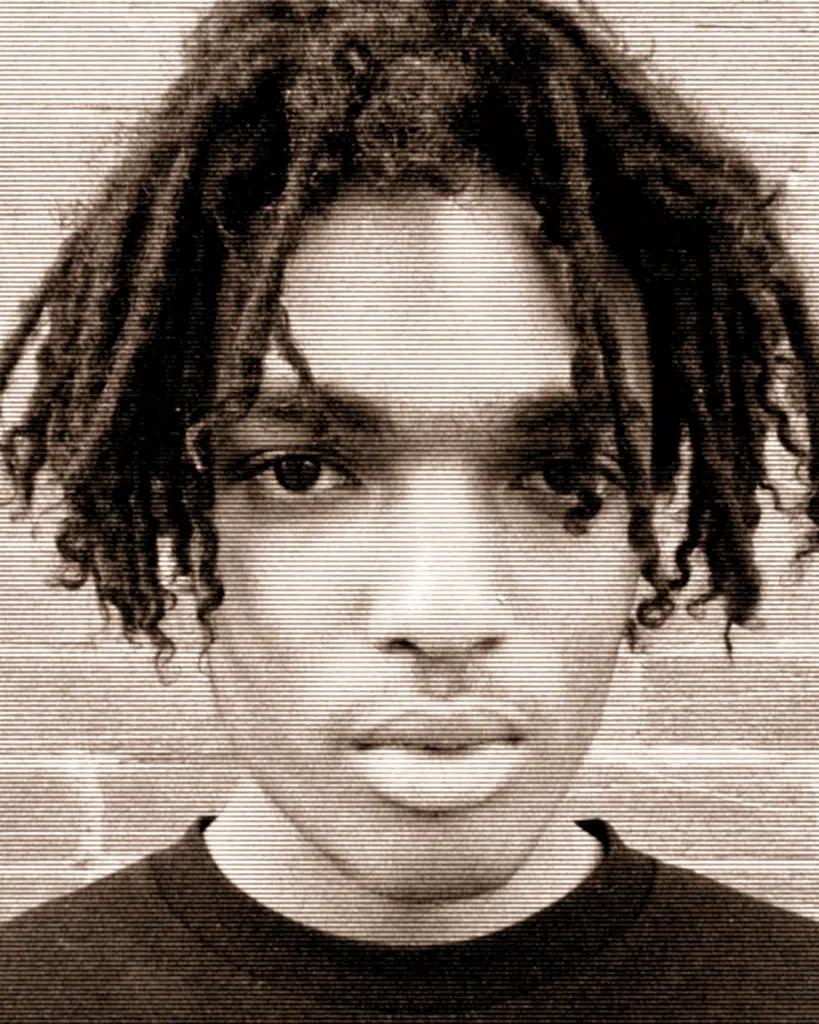 A young man with dreadlocks is looking at the camera.