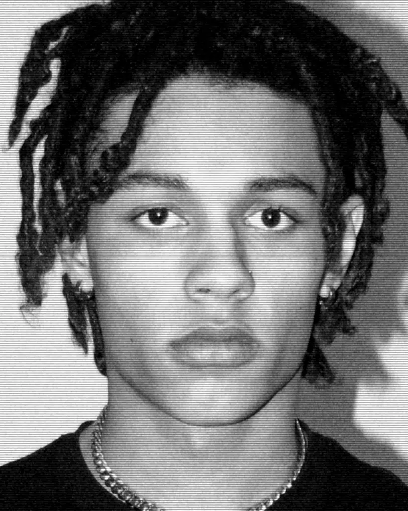 A young man with dreadlocks is looking at the camera.