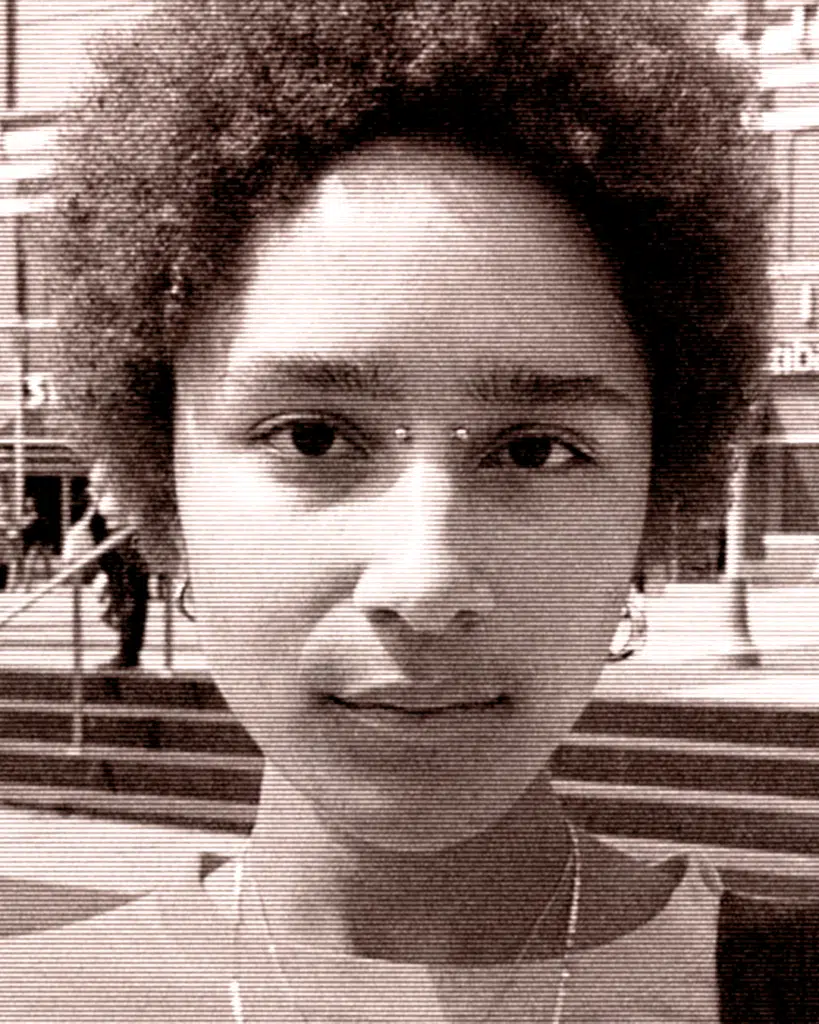 A woman with curly hair is standing outside.