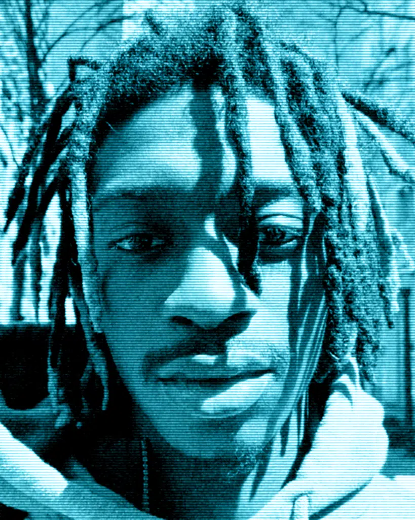 A man with dreads is looking at the camera.