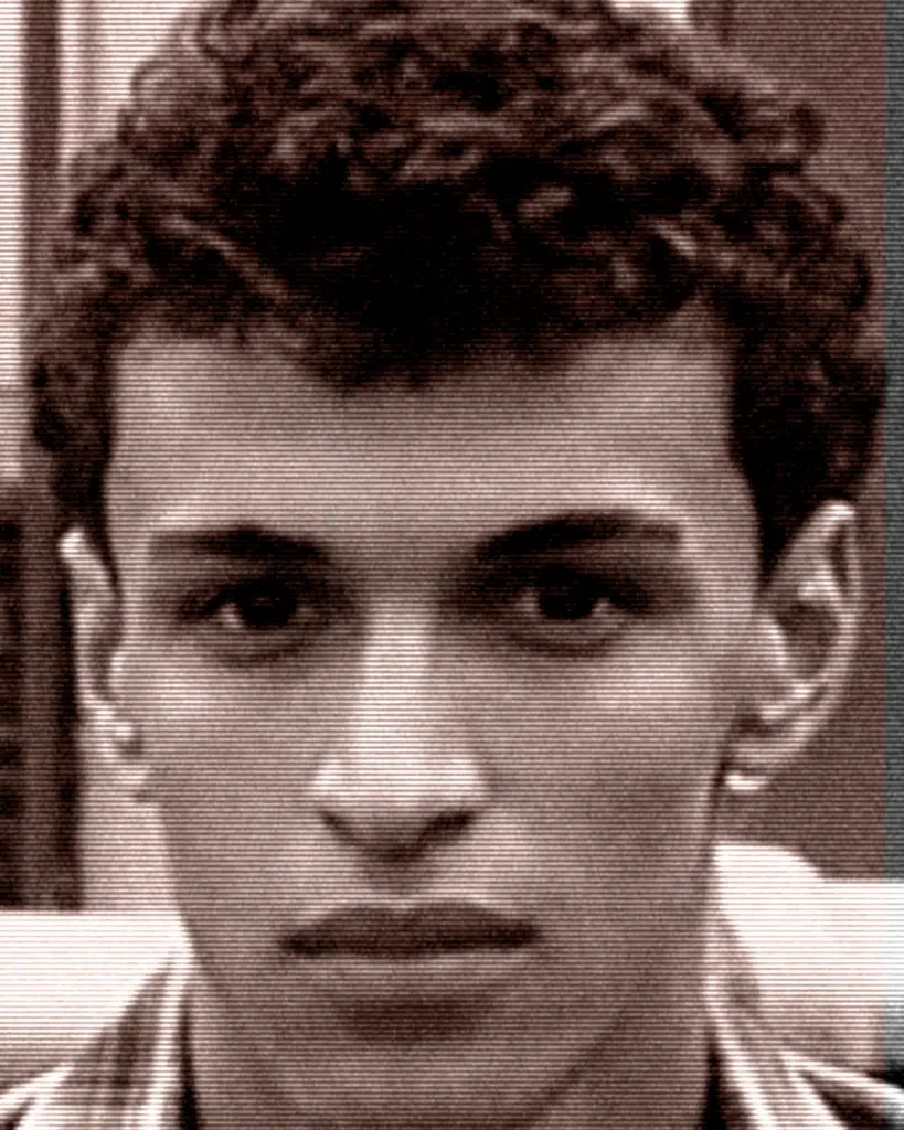 A young man with curly hair and a piercing.