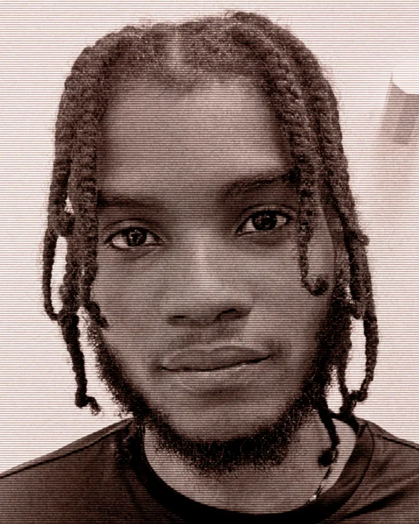 A man with dreadlocks is looking at the camera.