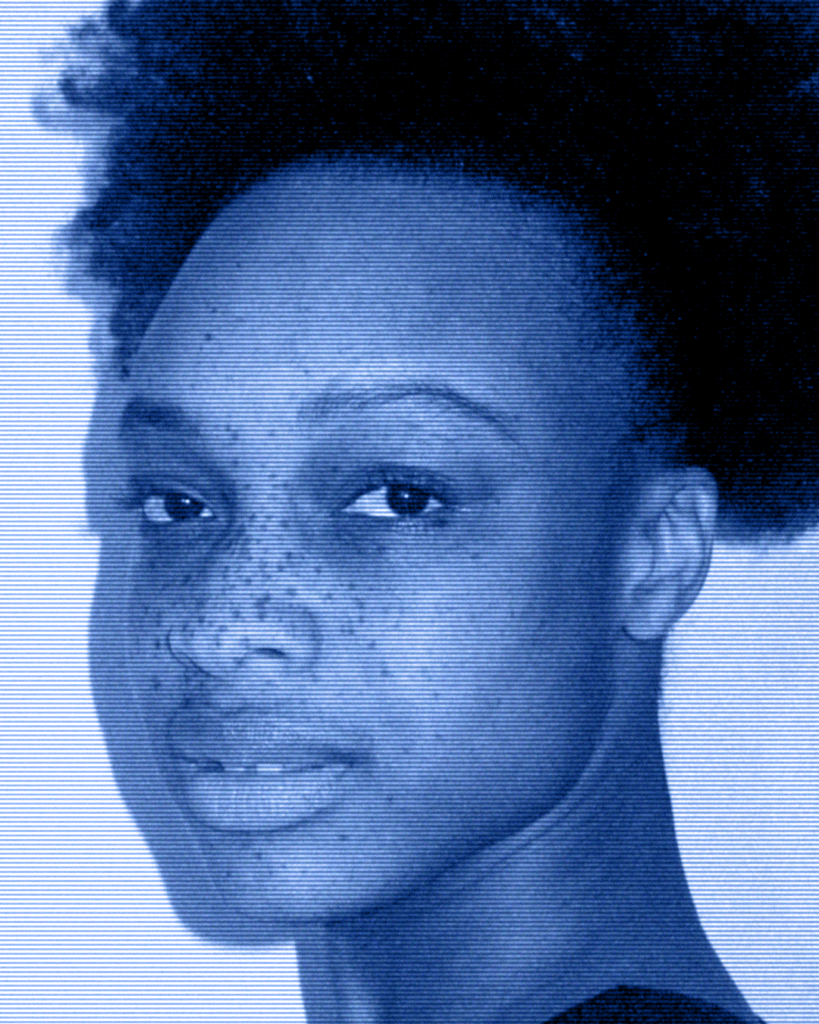 A woman with a very large afro is smiling.