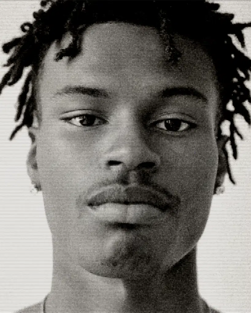 A black and white photo of a man with dreads.