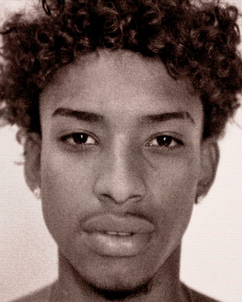 A young man with curly hair and a piercing.