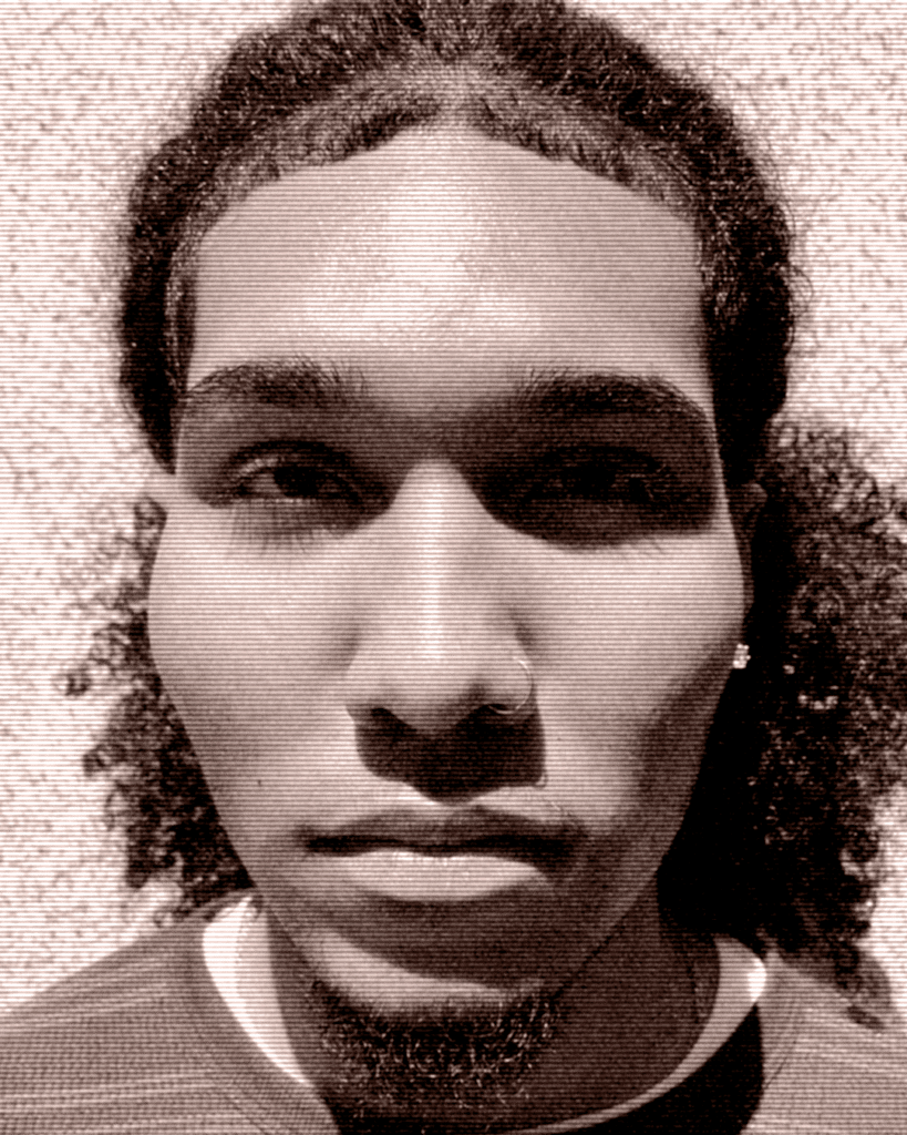 A man with long hair and piercing wearing a shirt.