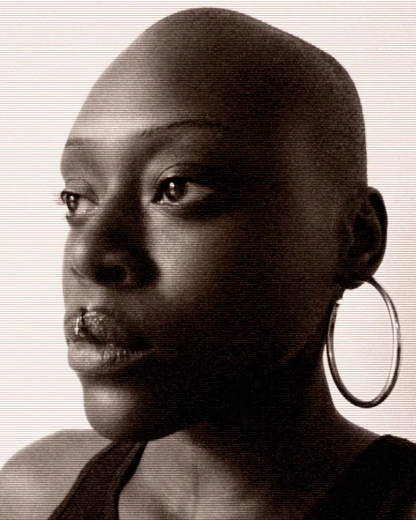 A woman with a shaved head and large hoop earrings.