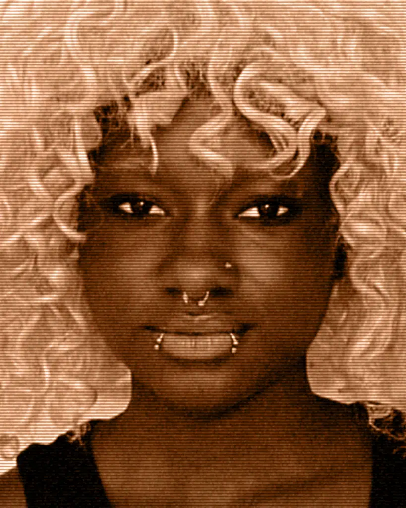 A woman with curly hair and piercing in her nose.