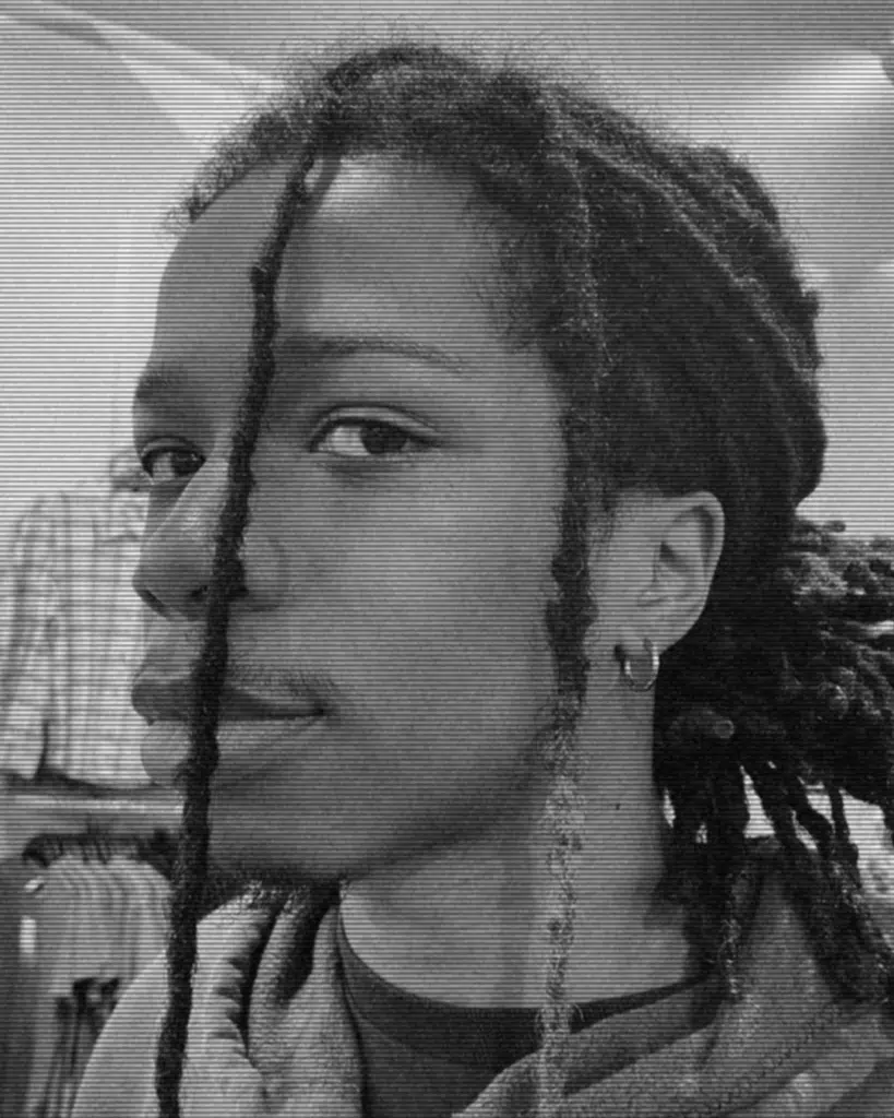 A black and white photo of a person with dreads.