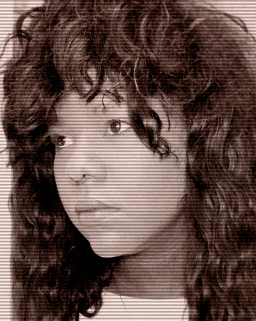 A young woman with long hair and a big, curly wig.