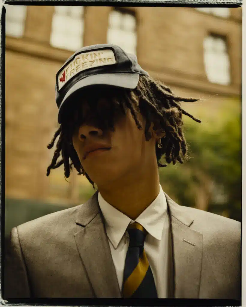 A man with dreads wearing a hat and suit.