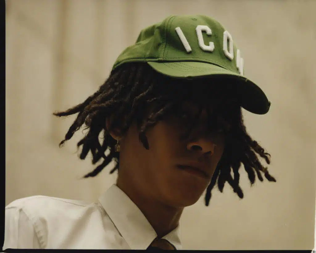 A man with dreads wearing a green hat.