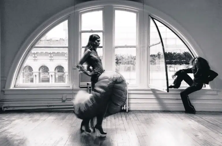 A woman in black lingerie and high heels standing on the floor.