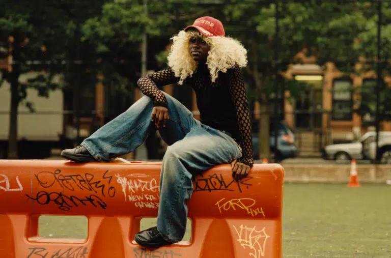 A man sitting on top of a red fence.