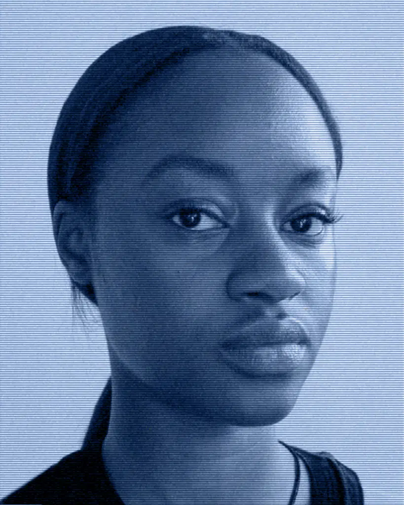 A woman with a blue background is looking at the camera.