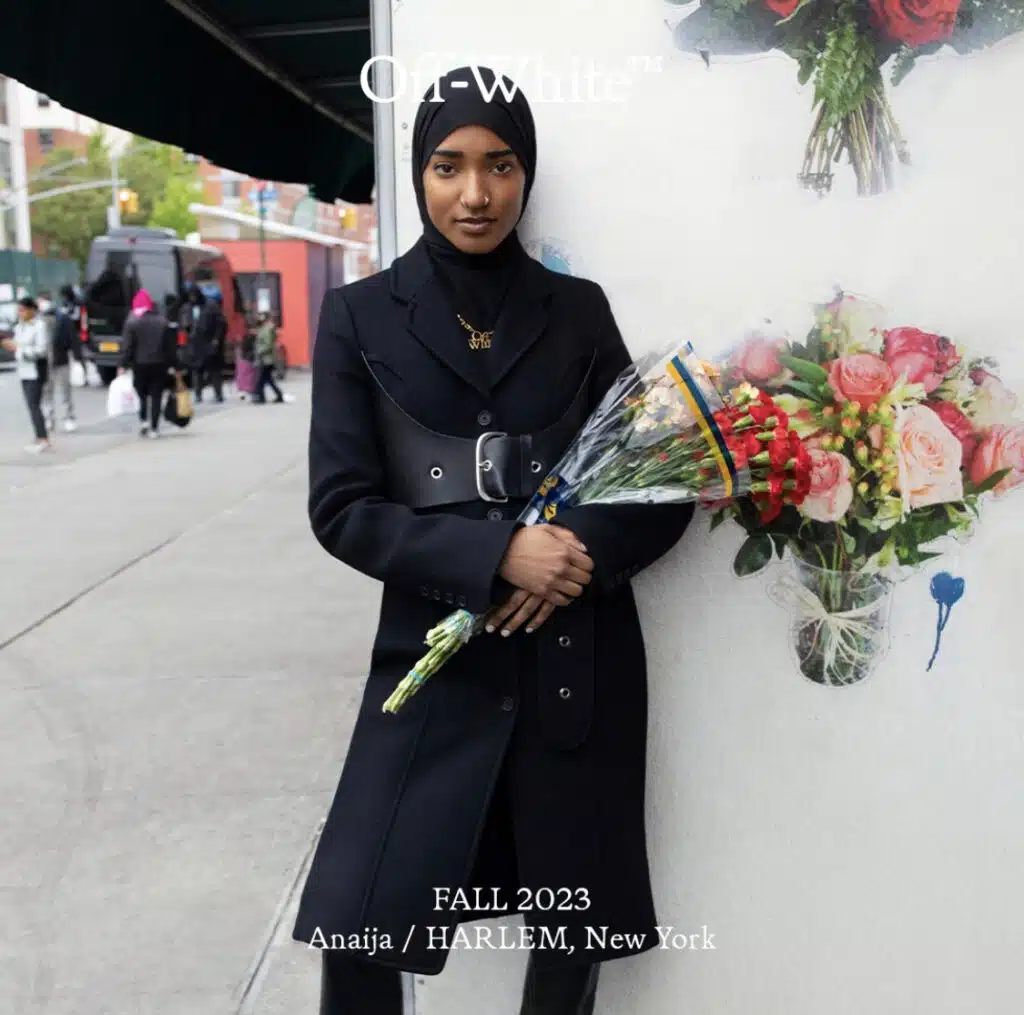 A woman holding flowers in her hand and wearing a black coat.