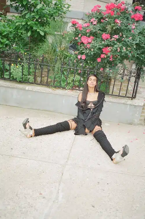 A woman sitting on the ground wearing knee high socks.