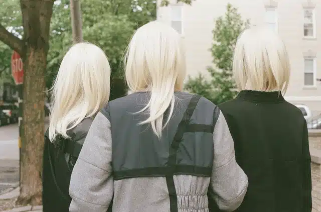 Three blonde haired women standing next to each other.