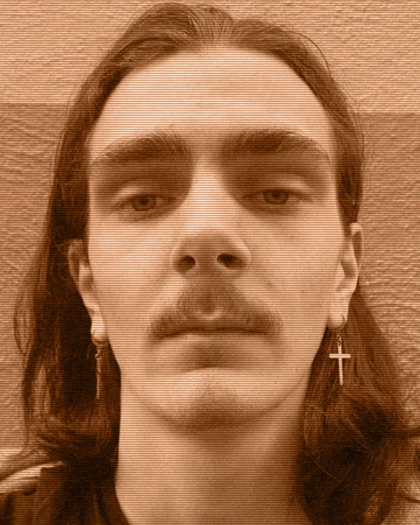 A man with long hair and cross earrings.