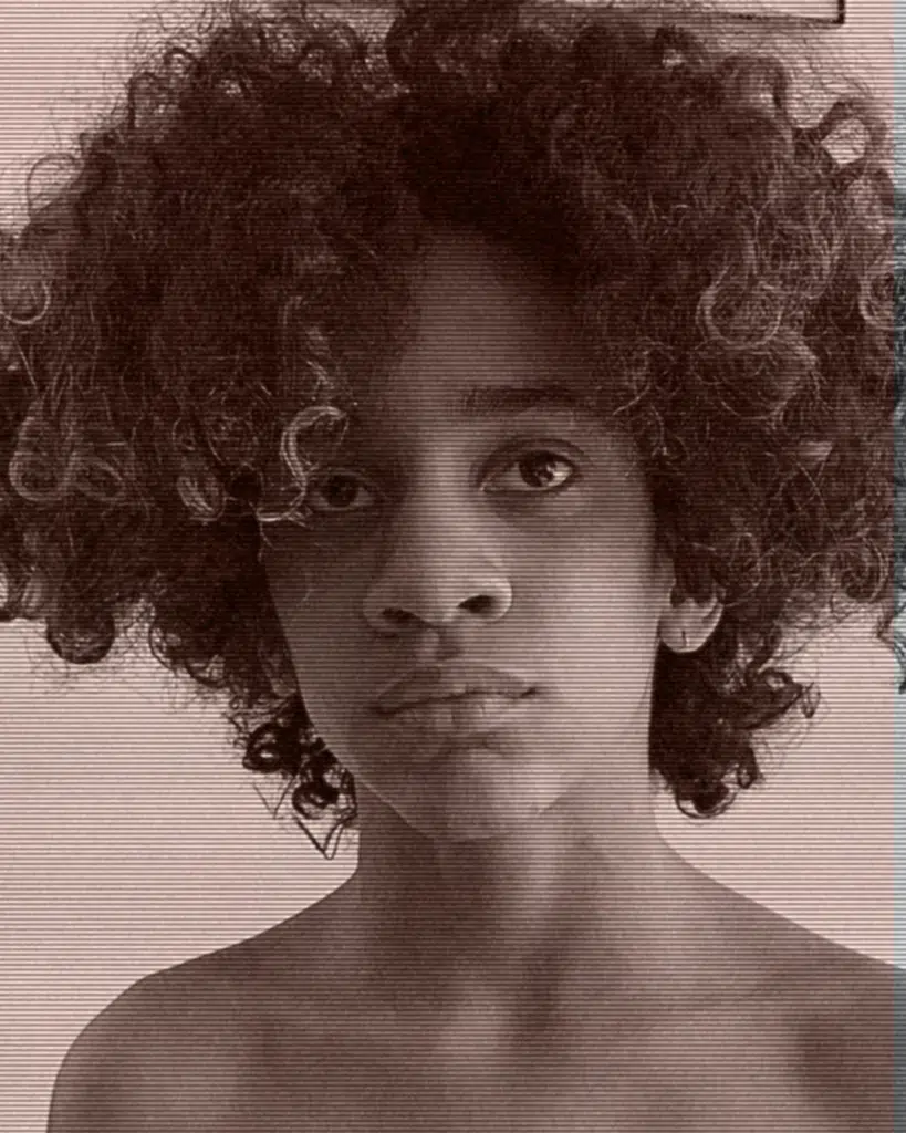 A young man with curly hair posing for the camera.