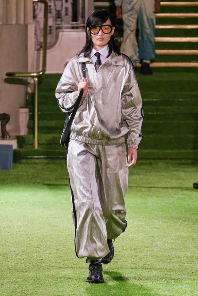 A man in silver suit and tie walking down the stairs.