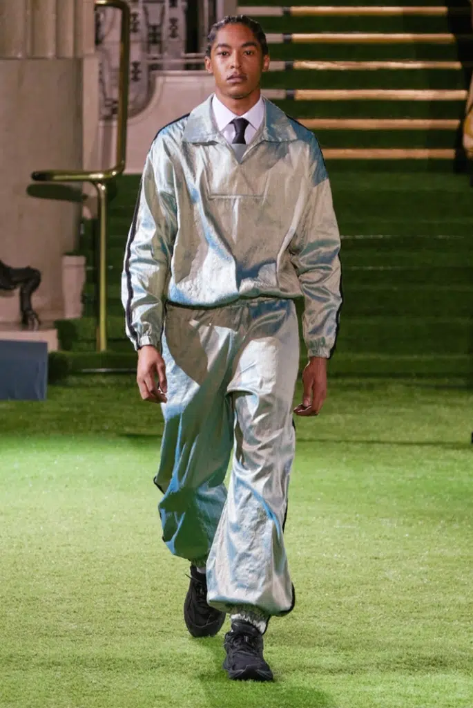 A man in silver suit walking on green grass.