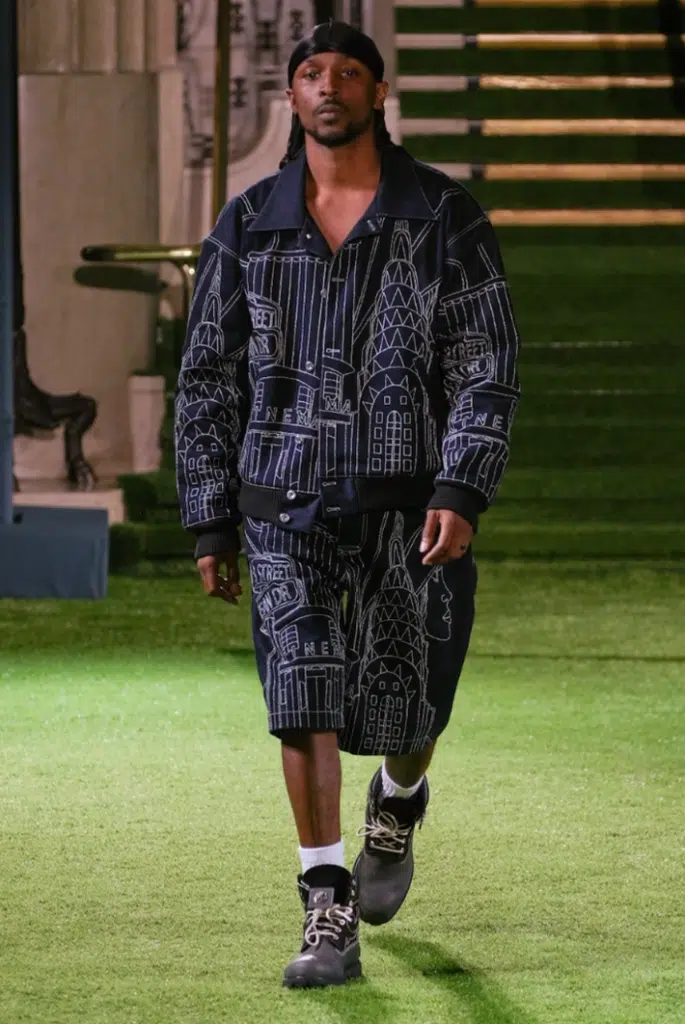 A man in black and white clothing walking down the runway.