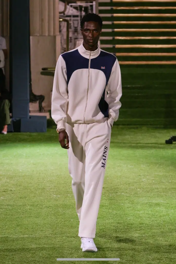 A man in white and blue outfit walking on grass.