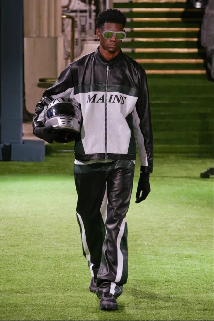 A man in black and white outfit holding a helmet.