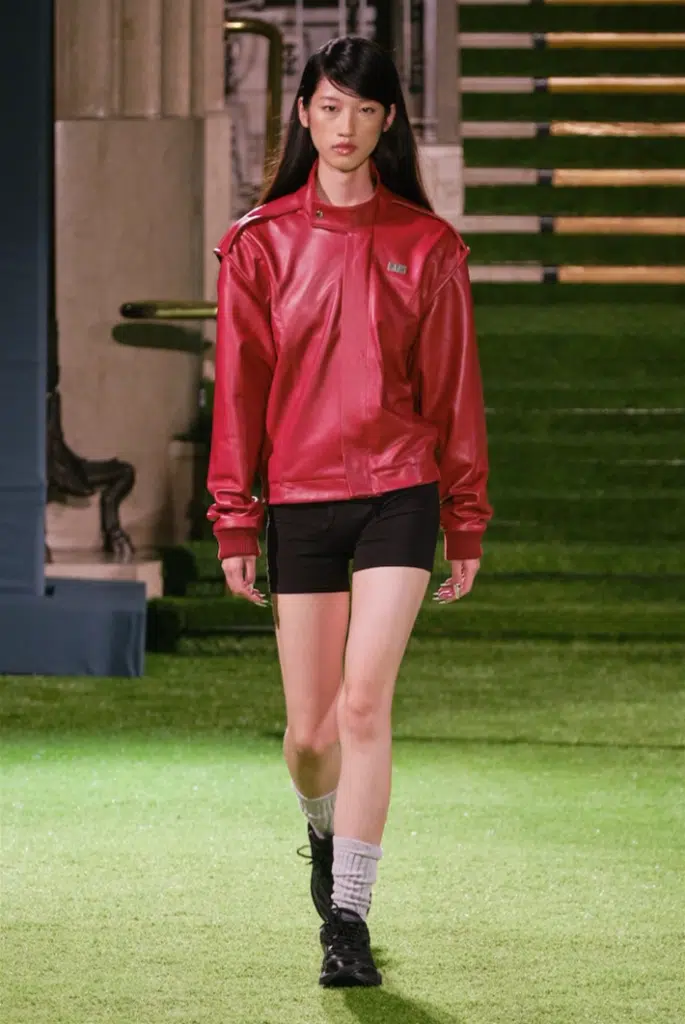 A woman in red jacket and black shorts.