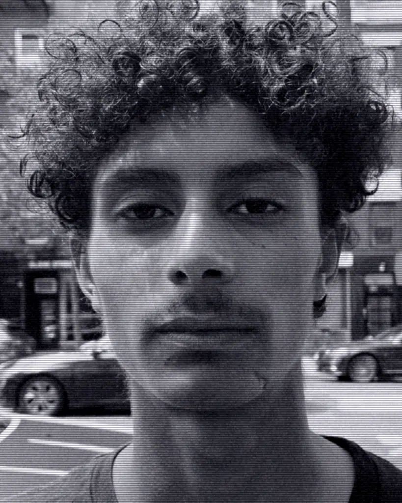 A man with curly hair is standing in the street.