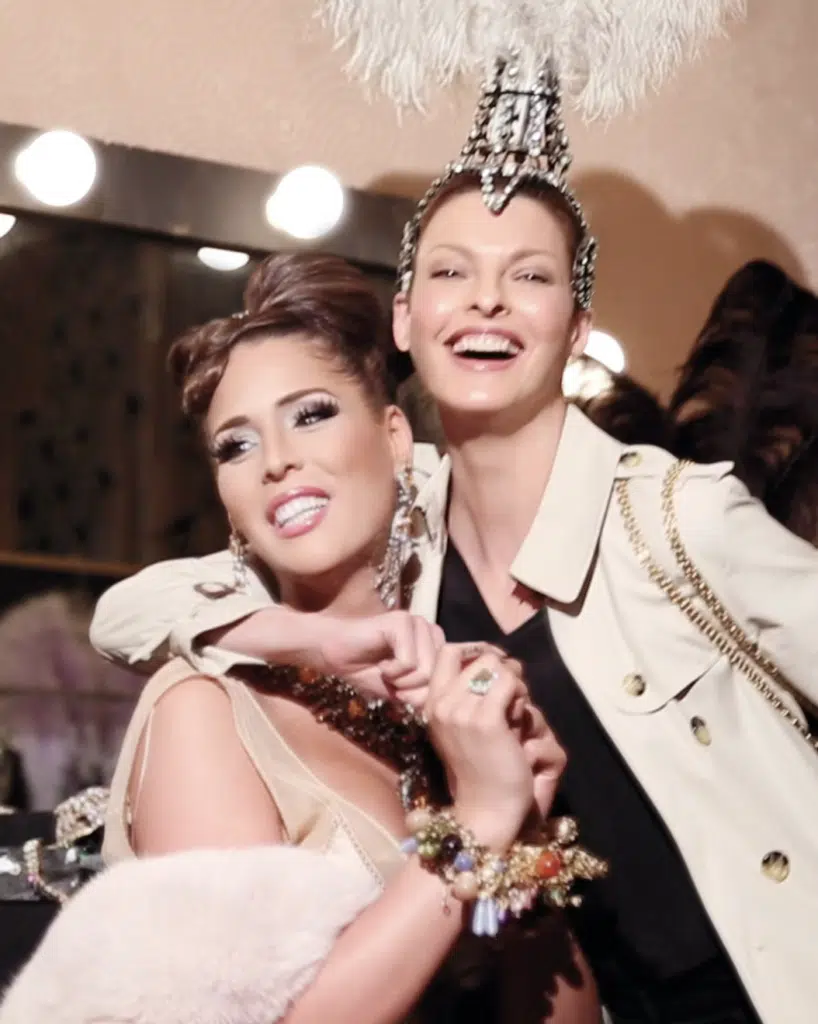 Two women posing for a picture in front of mirrors.