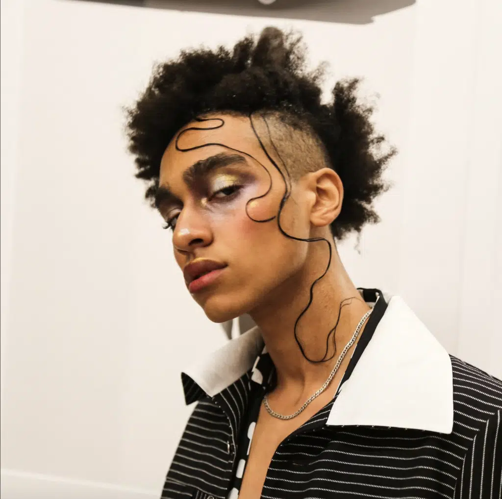 A man with an artistic haircut and makeup.