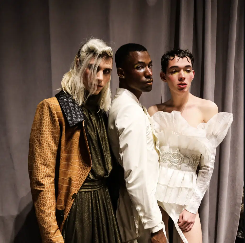 Three people posing for a picture in front of a curtain.