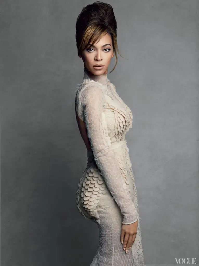 A woman in white dress standing next to wall.