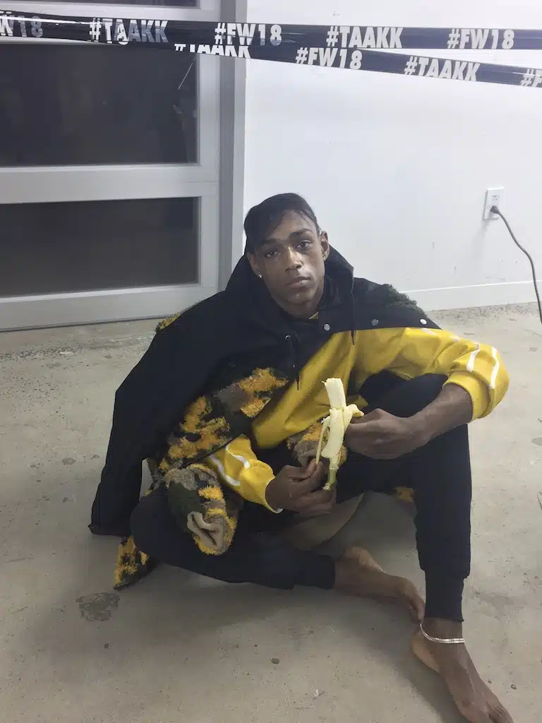 A man sitting on the ground holding a banana.