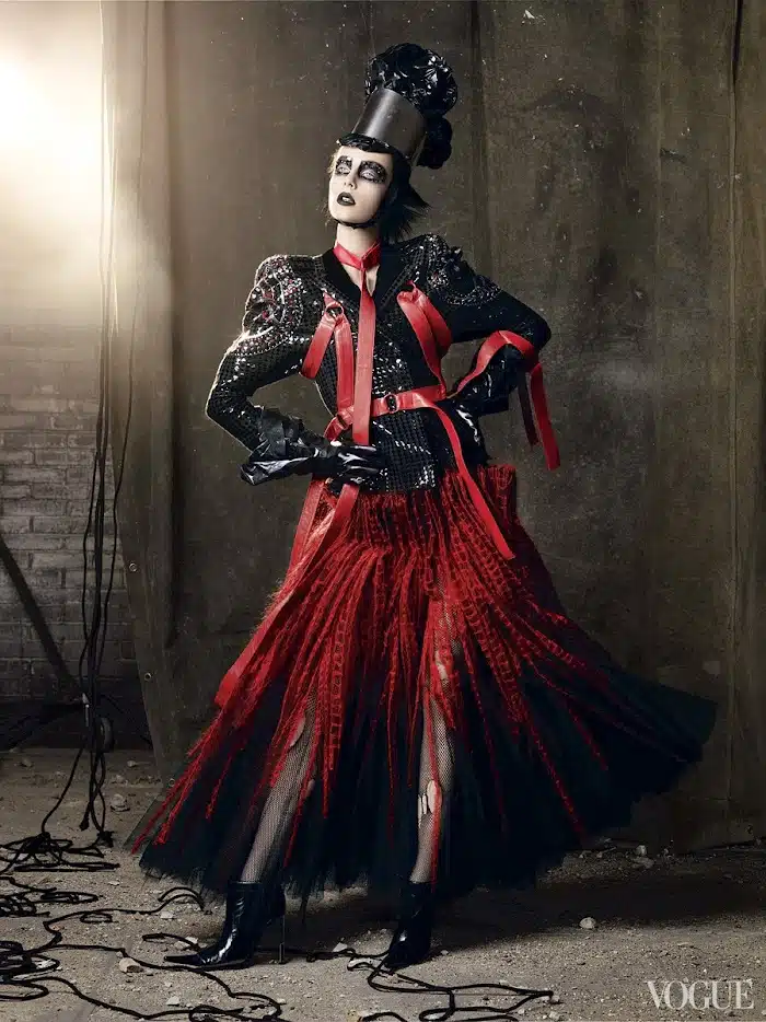 A woman in red and black costume standing next to a wall.