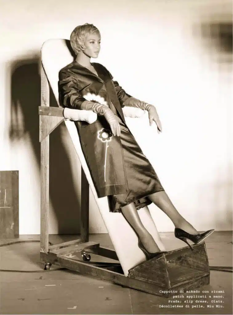 A woman sitting in an old chair with her legs crossed.