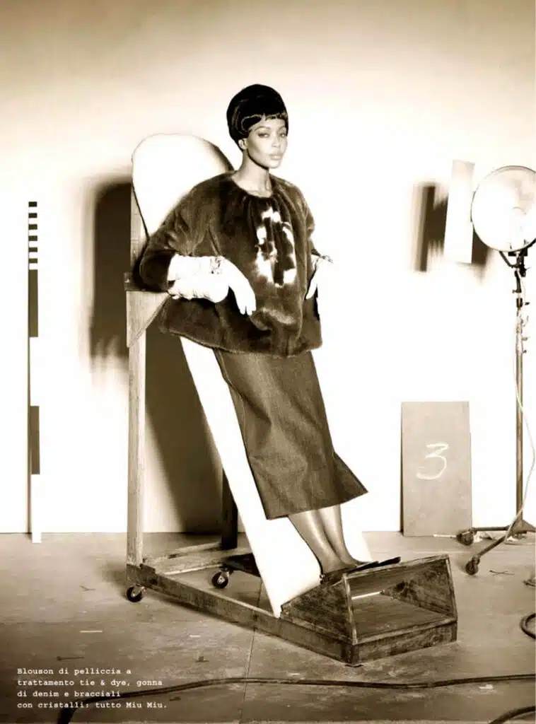 A woman in a dress and hat is sitting on a chair