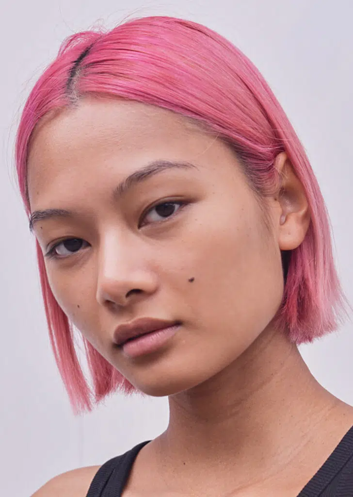 A woman with pink hair and black eye makeup.