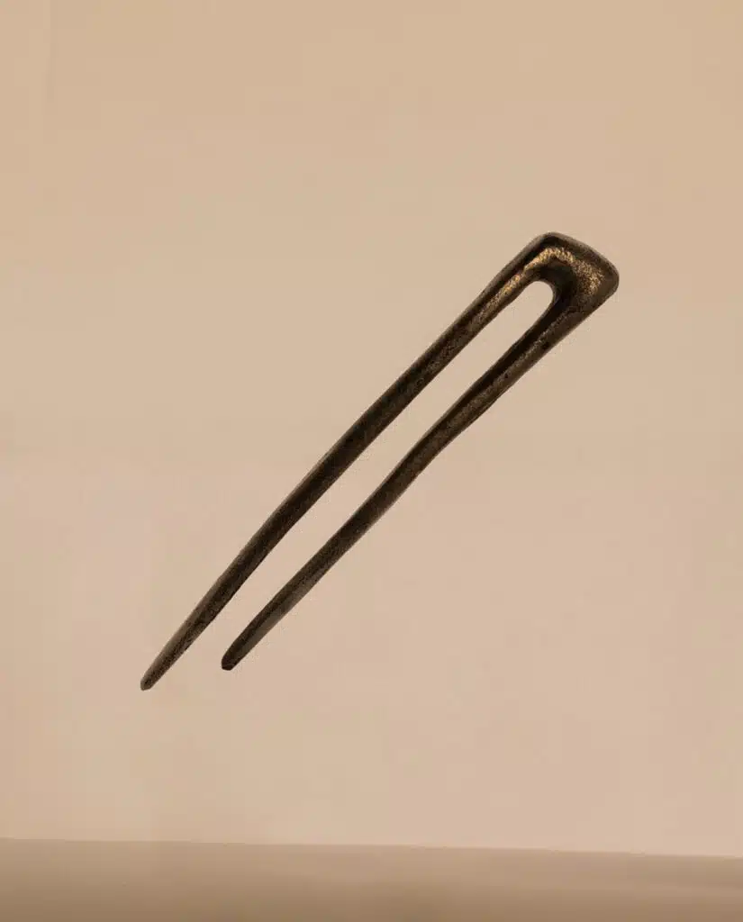 A black hair pin is on the ground.