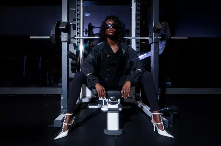 A man sitting on the bench in front of some weights.