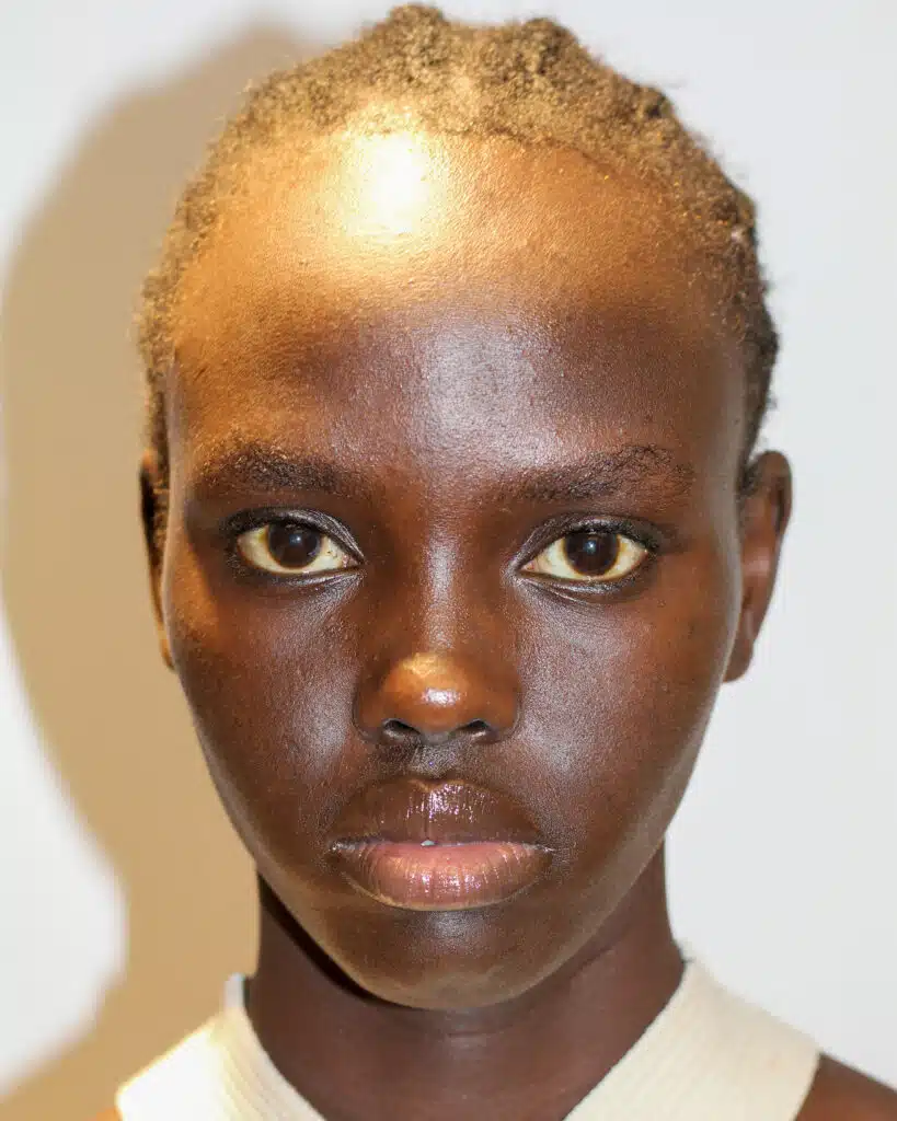 A young person with very dark skin and blonde hair.