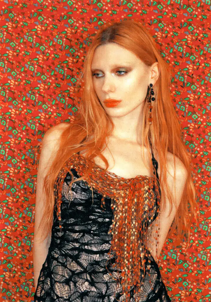 A woman with red hair and wearing a black top.