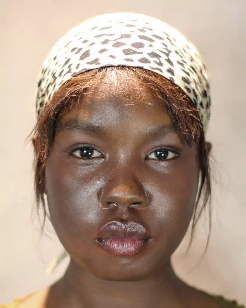 A woman with brown skin and a leopard print head scarf.